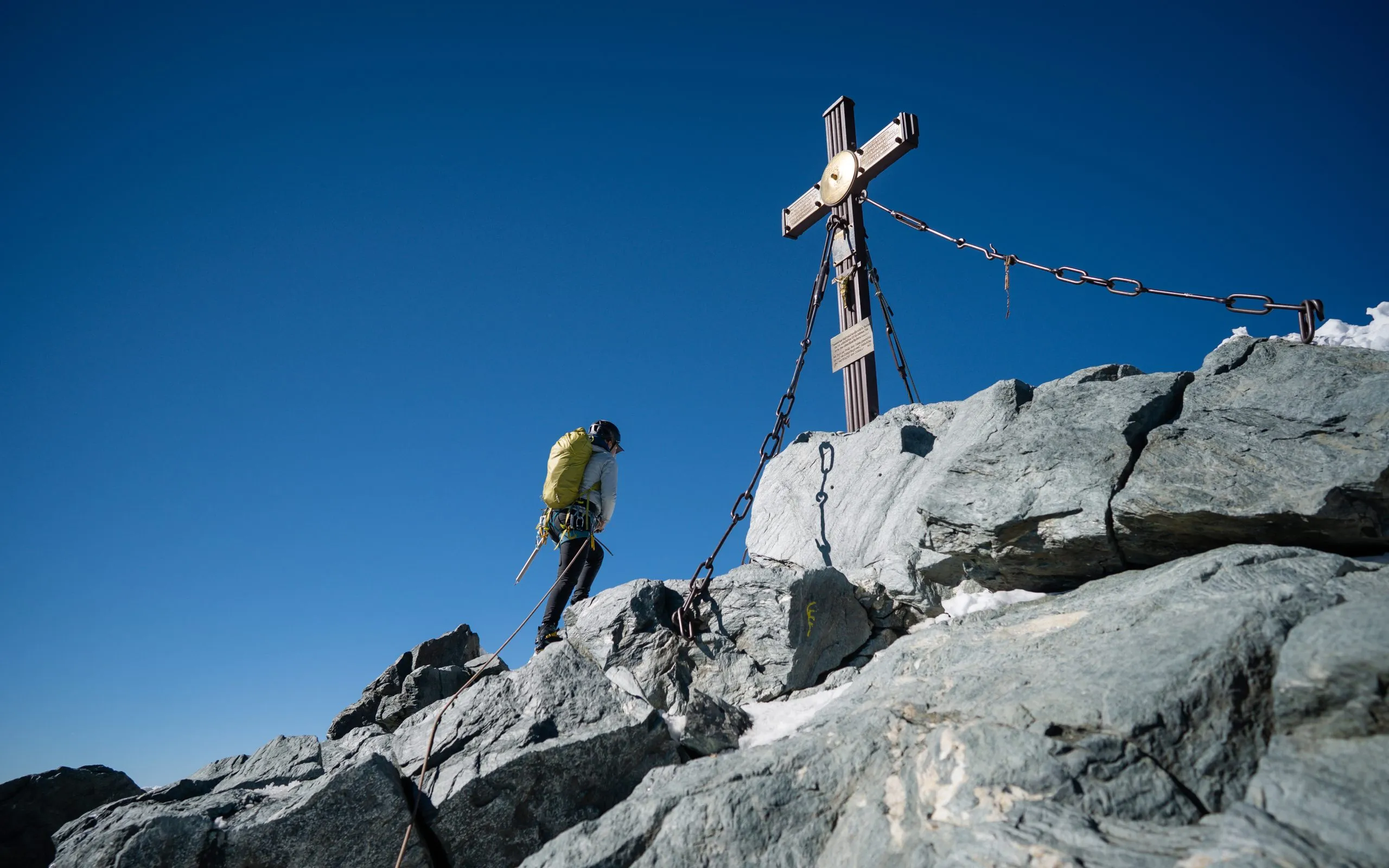 A woman in hiking outfit reaching the cross on Grossglockner, highest mountain in Austria. Clear day. Achievement. Girl on the top of peak