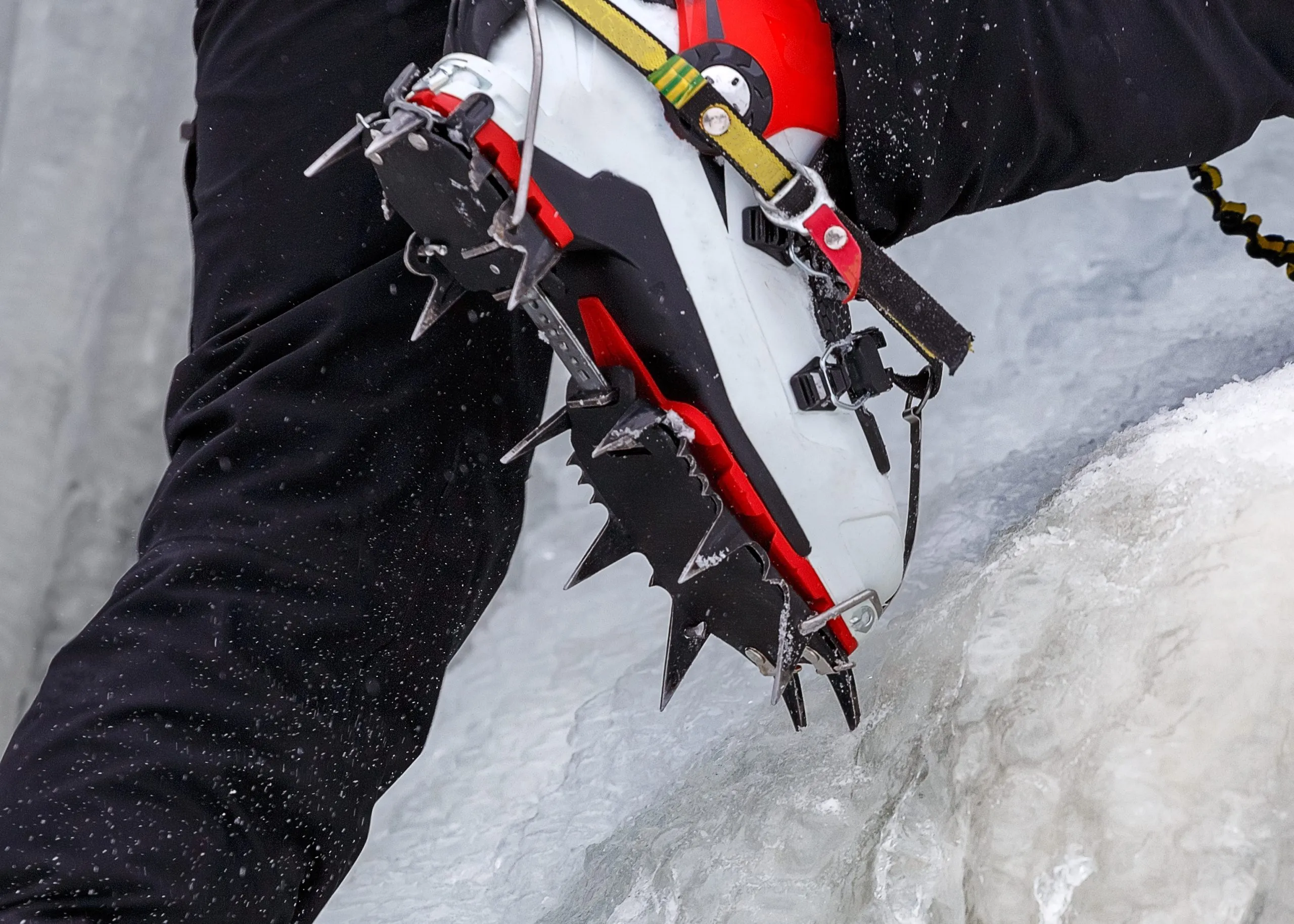 Horolezec na zamrzlém vodopádu. Skoby zblízka na nohou ledového lezce